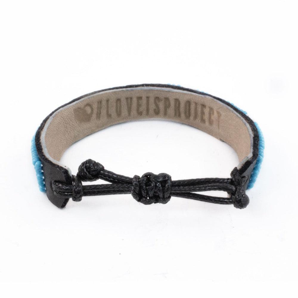 The inside of the blue AMOUR Bracelet says Love Is Project on the inside