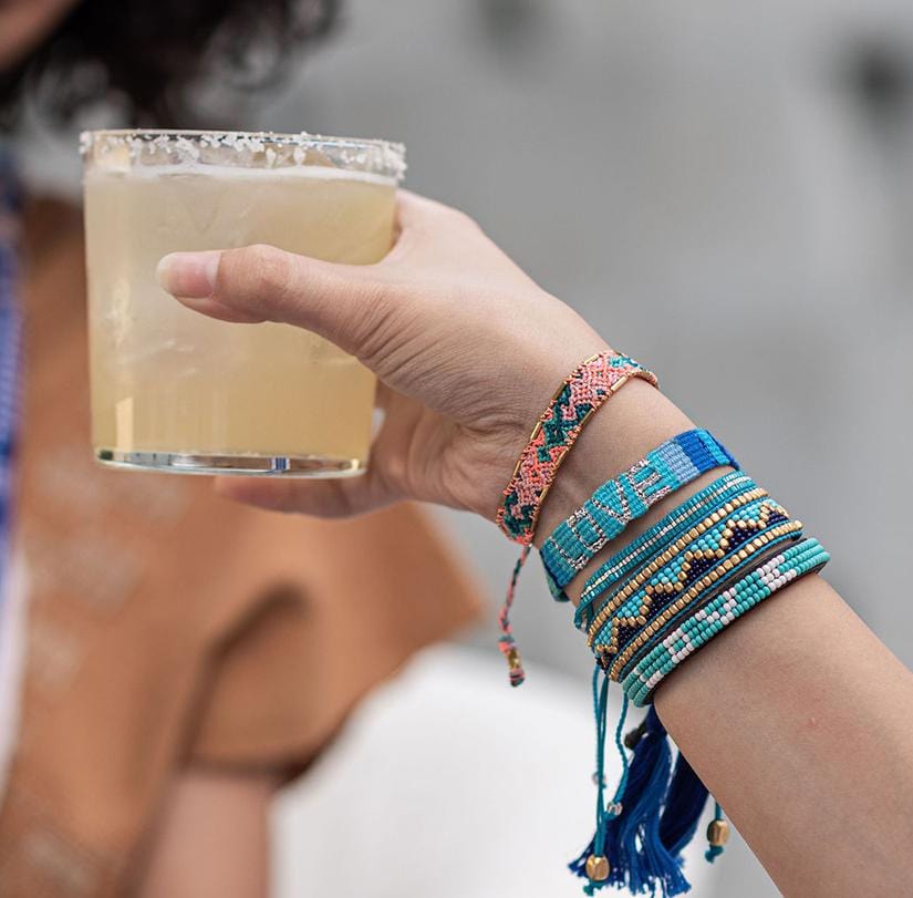 A model holding a drink and wearing a Blue, Turquoise, and Indigo Atitlan LOVE Bracelet from Love Is Project
