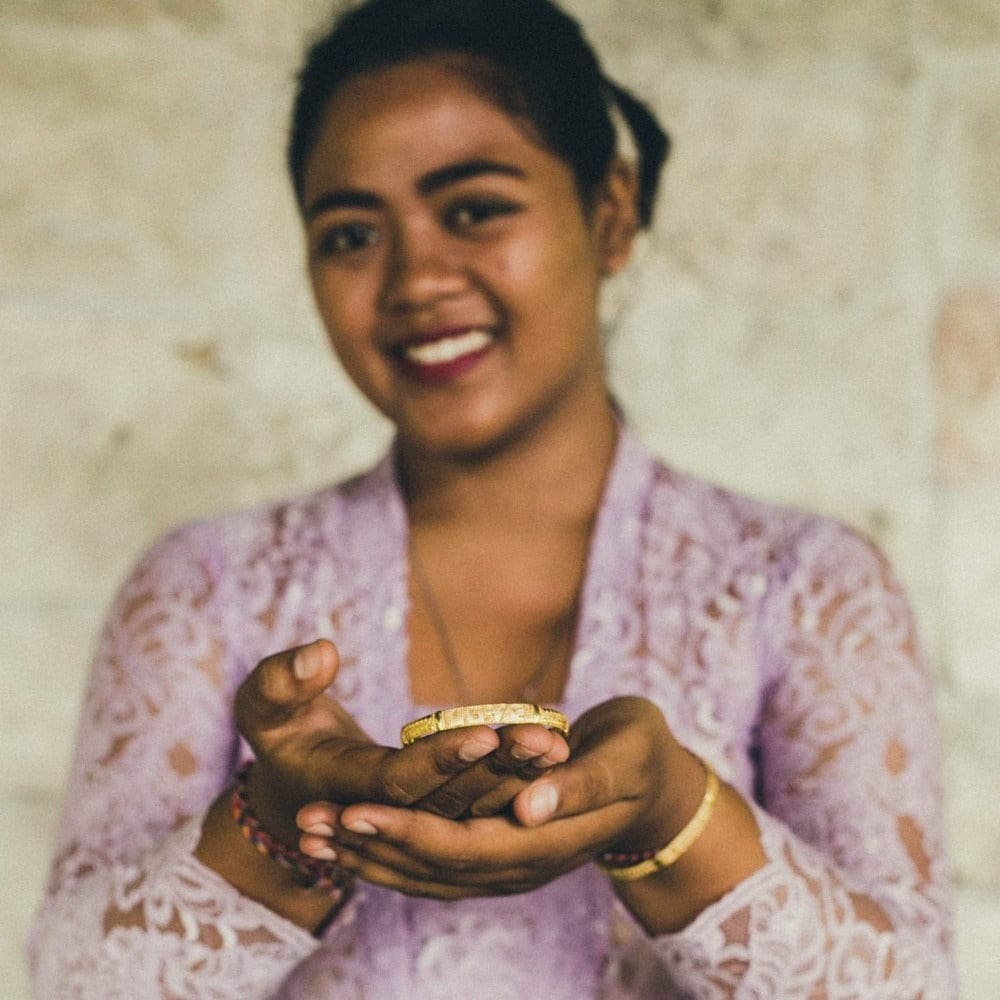 A Love Is Project Artisan holding a gold Alchemy LOVE bracelet