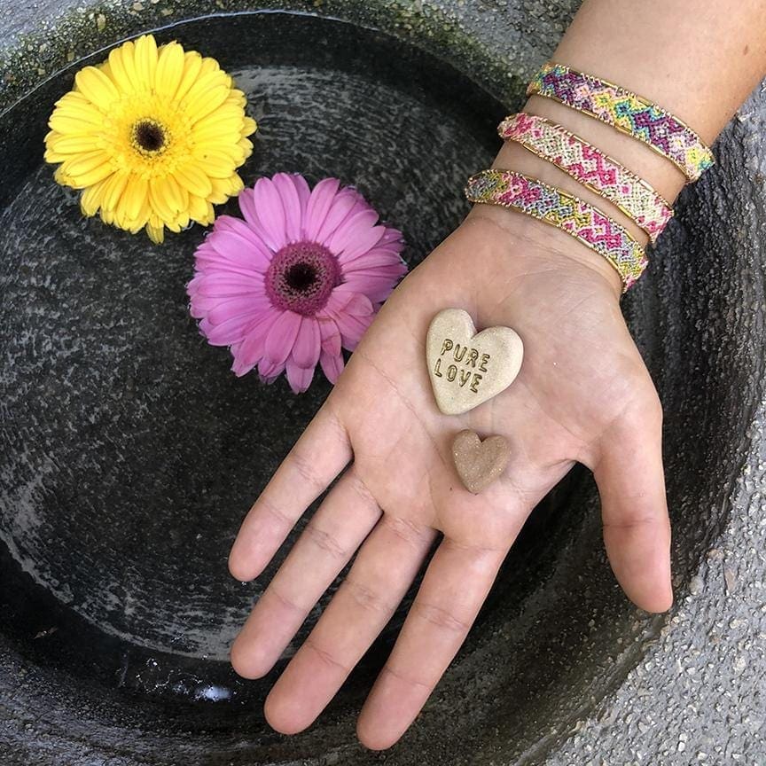 A model with flowers wearing the Bloom Violet Bali Friendship Bracelet from Love Is Project