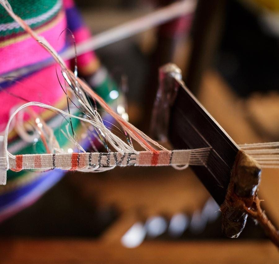 An artisan making the White, Peach, and Orange Atitlan LOVE Bracelet from Love is Project