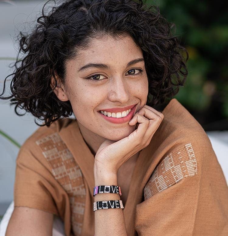 A model wearing the Black and Coral Atitlan LOVE Bracelet from Love Is Project