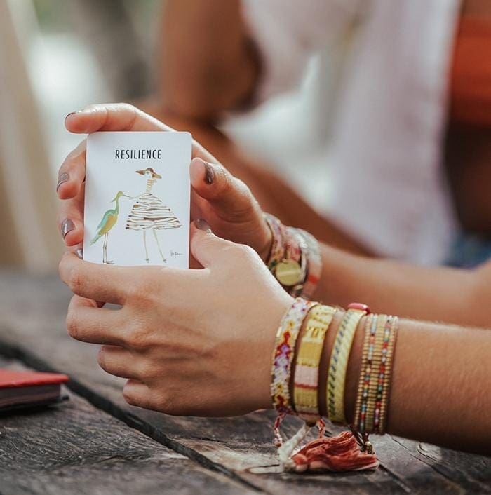 A model holding the Spread the Love Deck of Cards and wearing the Desert Gypsum Bali Friendship Bracelet from Love Is Project